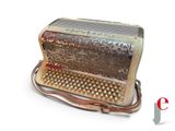 a silver and red accordion sitting on a white surface