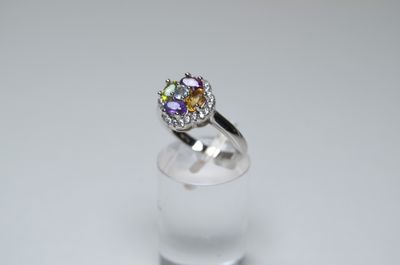 an image of a ring with multi colored stones on a clear glass