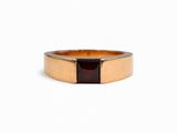 un gros plan d'une bague en or avec une pierre rouge au centre