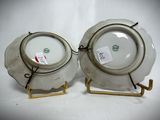 pair of white porcelain plates with gold rims on stands