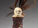 two figurines of people with long hair are on a stand
