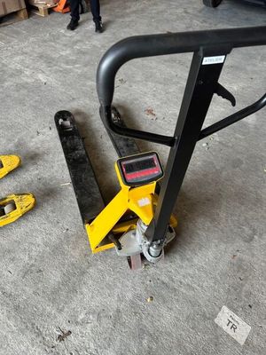 un diable jaune posé par terre à côté d'une paire de skis jaunes