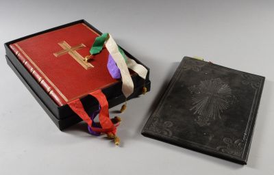 un livre noir à la couverture rouge, orné d'une croix dorée
