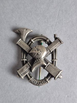 une broche en argent sur laquelle sont représentés un marteau et une clé à molette