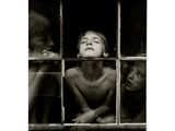 photographie en noir et blanc représentant trois enfants regardant par la fenêtre