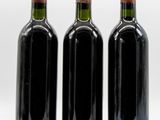 three bottles of wine are lined up in a row on a white surface