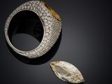 a diamond and gold ring with a leaf on a black surface