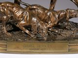 a bronze statue of two dogs running on a field