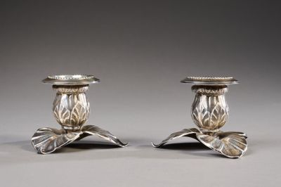 pair of silver candlesticks with leaves on each of them