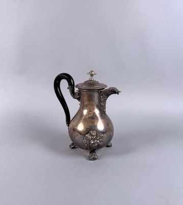 une cafetière ancienne en argent avec une poignée noire sur fond blanc