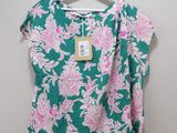 a green and pink floral top hanging on a hanger