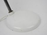 a white floor lamp with a black handle on it