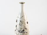 un vase blanc orné d'un motif noir et blanc, à côté d'une feuille verte