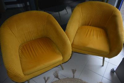 pair of yellow chairs in a living room with a rug on the floor