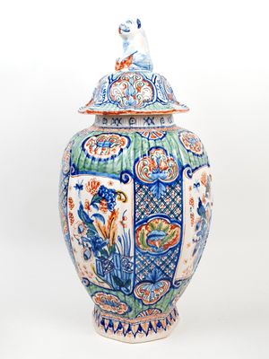 a blue and white vase with a bird on top of it
