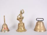 three brass bells sitting next to each other on a white surface