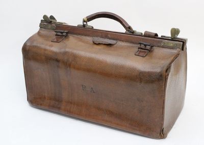 une valise marron posée sur une surface blanche