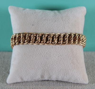 gros plan d'un bracelet en chaîne en or sur un oreiller