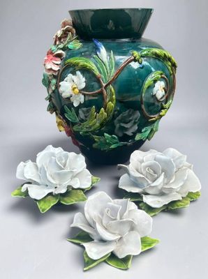a green vase with white flowers on the side of it