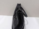 black leather handbag on a white table with a white wall