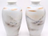 two white vases sitting next to each other on a white surface