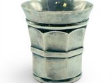 une tasse en argent posée sur une surface blanche