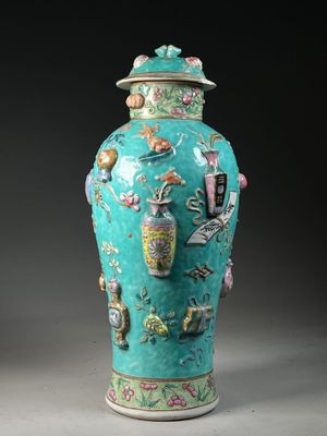 a green vase with a lid that has a picture on it