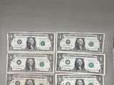 four bills of one hundred dollars are on display in front of a refrigerator