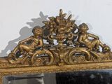 a mirror that has a gold frame with a picture of cherensils on it