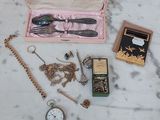 une table sur laquelle sont posés plusieurs objets, notamment une montre, une montre de poche, une chaîne de montre, une montre de poche et une montre