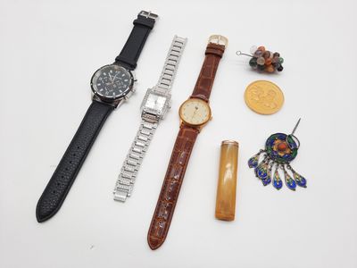 trois montres, une montre, un bracelet et d'autres bijoux sont posés sur une surface blanche
