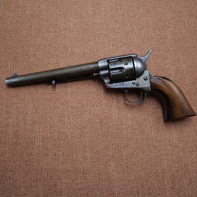 an old revolver with a wooden handle on a brown surface