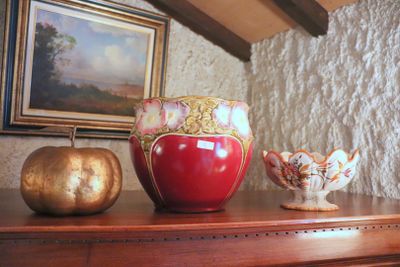 a red vase sitting on top of a table next to a gold pumpkin