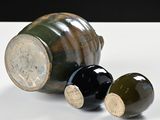 three black and green vases sitting on a white table