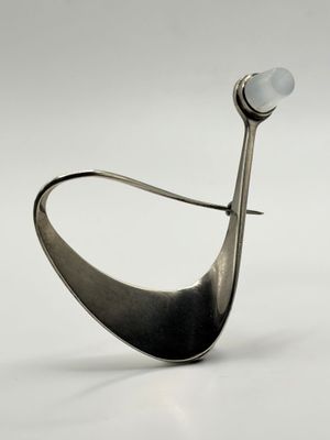 silver spoon with a white stone on it sitting on top of a white surface