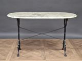 an oval marble table with iron legs on a parquet wood floor