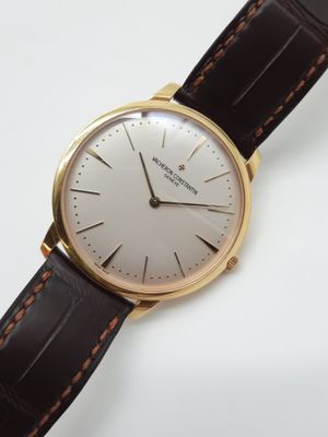 gros plan d'une montre sur une surface blanche avec un bracelet marron