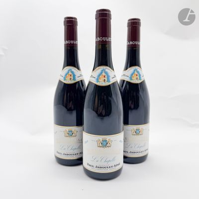 trois bouteilles de vin rouge posées l'une à côté de l'autre sur une surface blanche