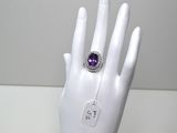 une image représentant une main blanche avec une bague violette au doigt