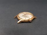 a gold watch on a black surface with a black background