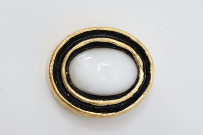 black and white button with gold trim on a white surface