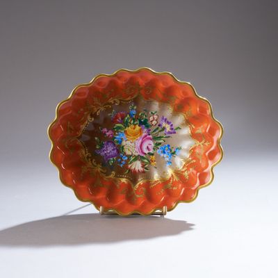 une assiette orange décorée de fleurs, posée sur une surface blanche