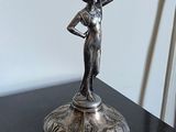 une statue représentant une femme tenant un pot posé sur une table