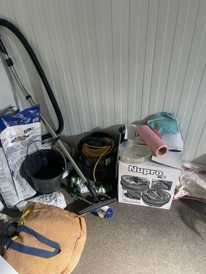 un tas d'objets par terre, à côté d'un aspirateur