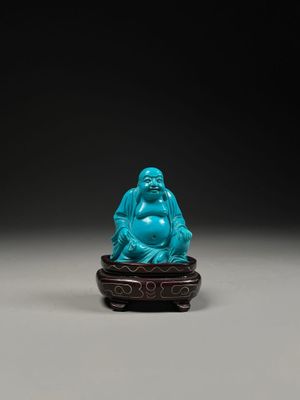 a blue jade figure of a laughing buddha on a stand