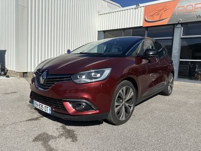 une voiture rouge garée devant un immeuble, sur un parking