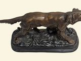 bronze statue of a dog standing on a rock on a white background