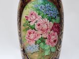 un vase sur lequel sont peintes des fleurs sur fond blanc
