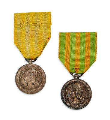 two medals are shown on a white surface with a yellow ribbon