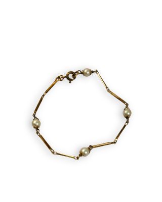 a gold bracelet with pearls on a white background